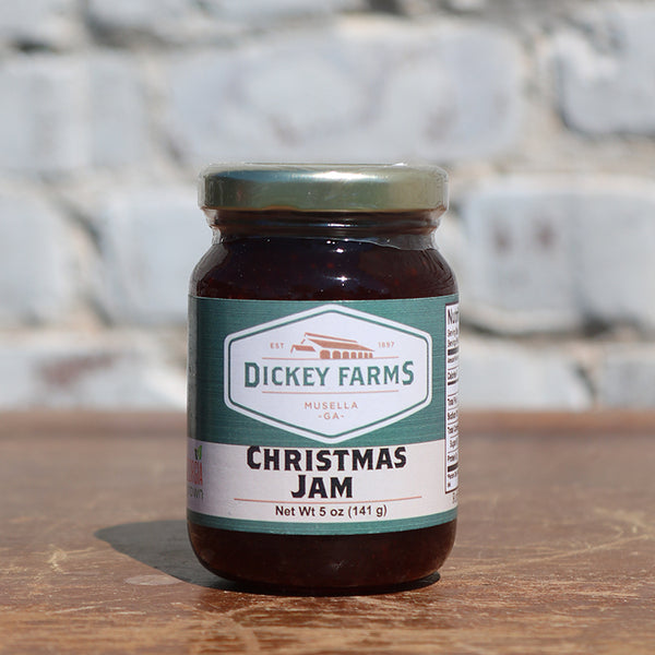 a jar of dickey farms christmas jam sits on a wooden table