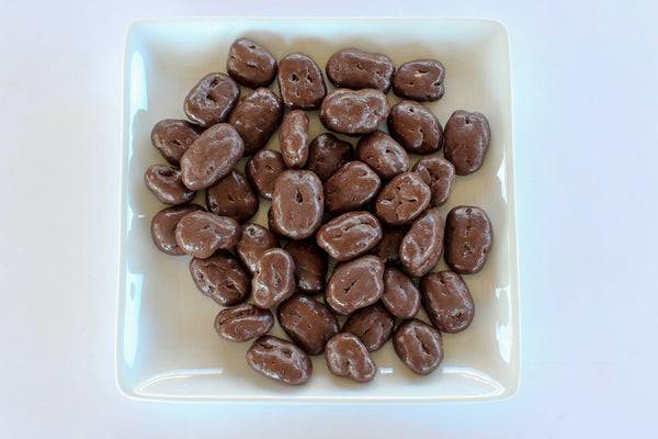 a pile of chocolate covered nuts on a white plate .