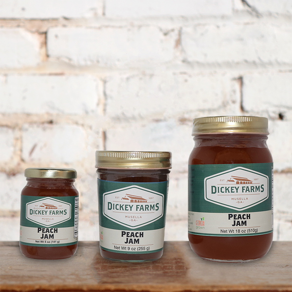 three jars of dickey farms peach jam on a wooden table