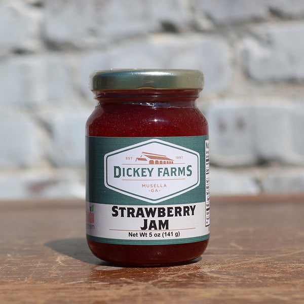 a jar of dickey farms strawberry jam sits on a wooden table