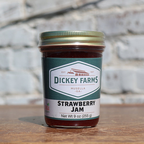 a jar of dickey farms strawberry jam sits on a wooden table