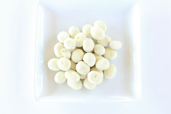 a pile of white chocolate pecans on a white surface .
